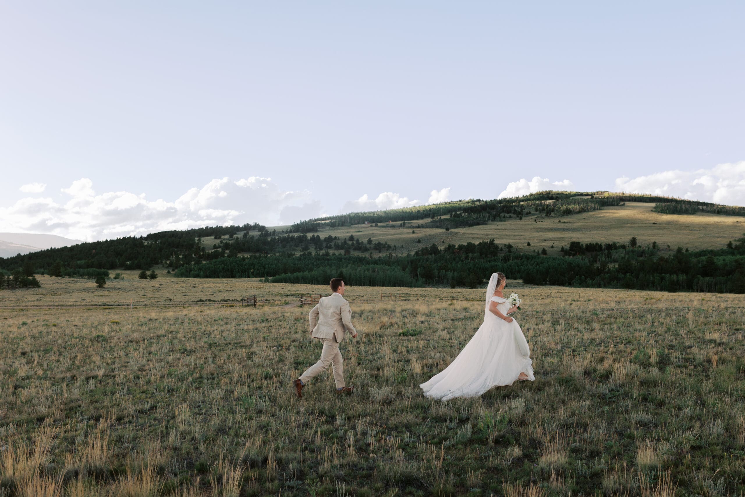 Bride and groom running through a valley in Breckenridge