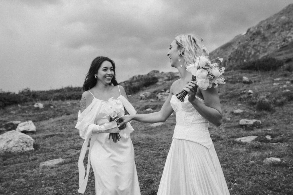 Two brides in the Colorado Rocky mountains laughing and looking at each other